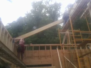Carpenter raising a rafter beam on a new second story frame in Forest Hill