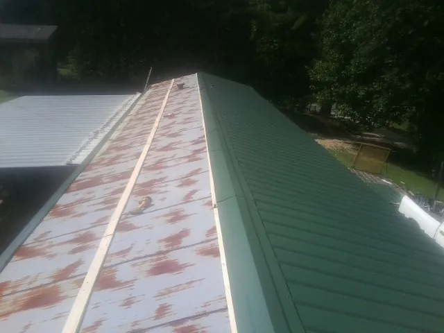 Old rusted panels beside newly installed green metal roofing — Wind Damage Roof Repair by Roofing Brothers in Forest Hill
