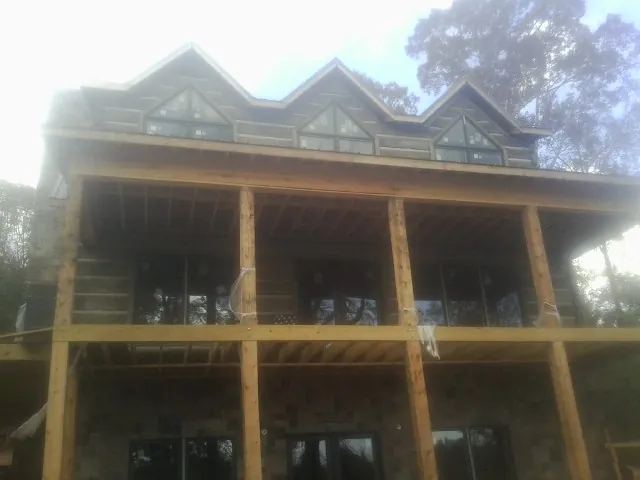 Dormers and porch framing on a large log home under construction — Roof Coating work by our crew in Forest Hill