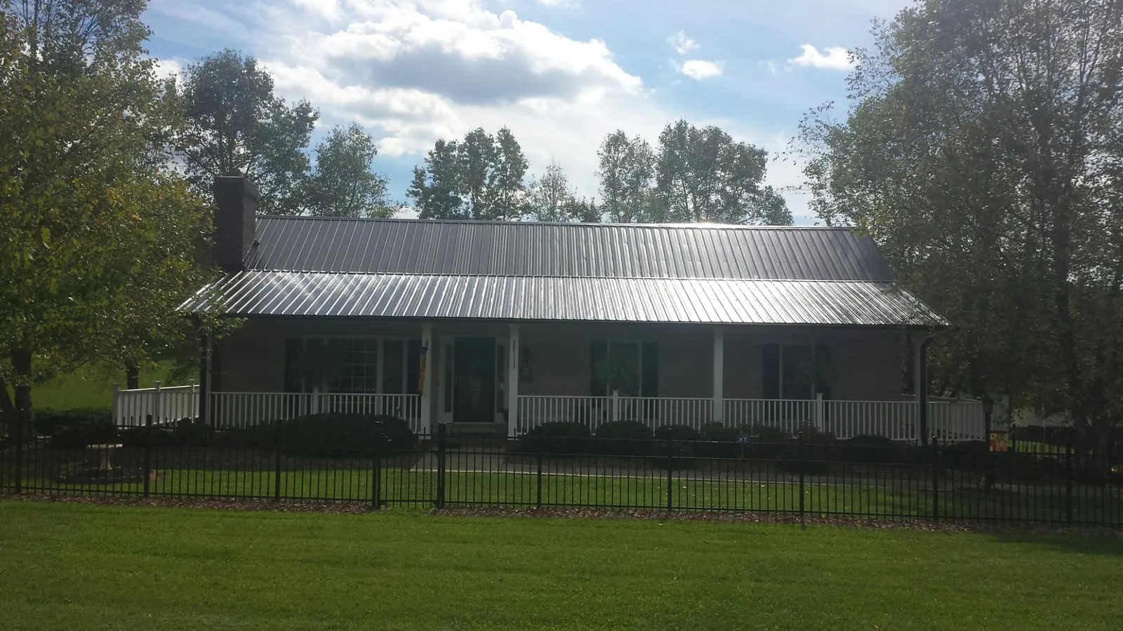 Gray metal roof on a brick ranch with a full width front porch — Gutter Guard Installation work by our crew in Forest Hill