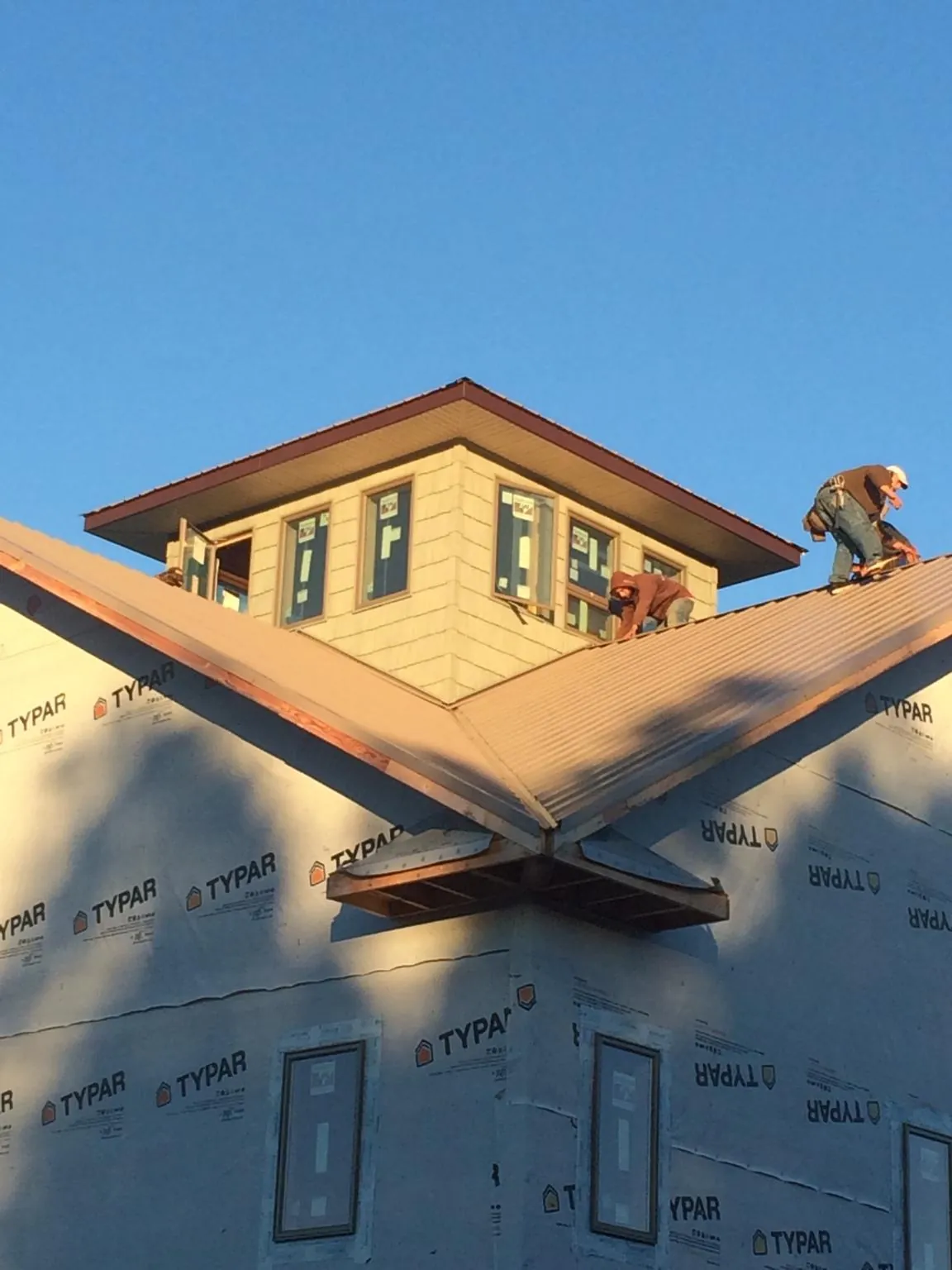 Roofers working around a rooftop cupola on a new metal roof at sunset — Roof Waterproofing in Forest Hill by Roofing Brothers